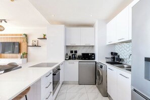 A modern kitchen with white cabinetry, a built-in oven, a dishwasher, and a microwave. - Horizon Haven with stunning view by HMH (Cape Town)