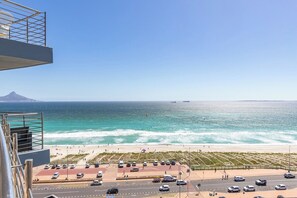 A coastal view with a beach, parking area, and a mountain in the distance. - Horizon Haven with stunning view by HMH (Cape Town)