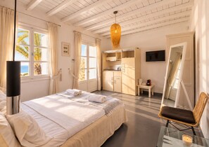A bedroom with a bed, a bedside table, a chair, a wardrobe, a television, and a window with curtains.