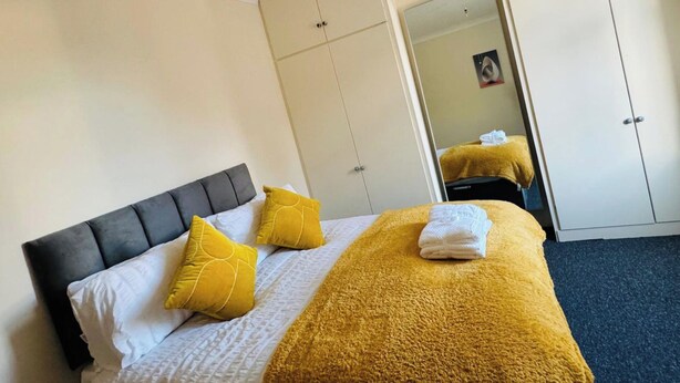A hotel room with a bed, a wardrobe, and a mirror. - 2 Bedroom House - Sleeps 4 - Free Parking, Wifi (Leicester)