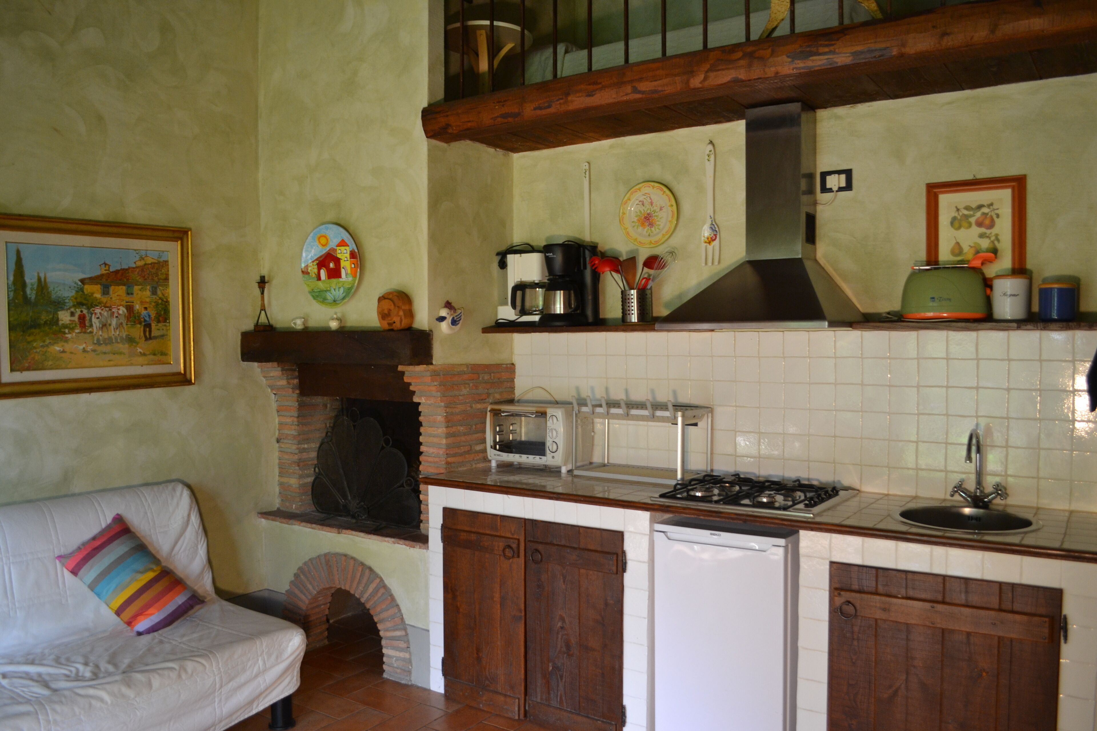 A kitchen with a brick oven, a toaster, a sink, and a stove.
