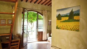 Una habitación con techo de madera, una mesa de comedor con sillas, un cuadro de un campo y una puerta que da al exterior.