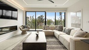 A modern living room with a large flat-screen TV, a ceiling fan, a sofa, and a coffee table.