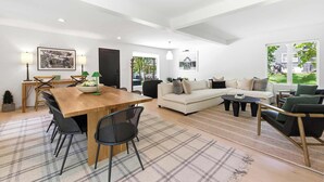Amplia sala de estar con una mesa de comedor de madera, sillas negras, un sofá y una mesa de centro.