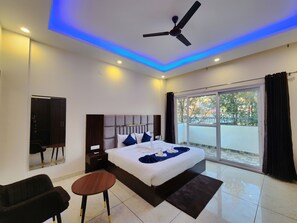 Ein modernes Schlafzimmer mit einem großen Bett, einem Deckenventilator und Blick ins Freie durch eine Schiebetür.