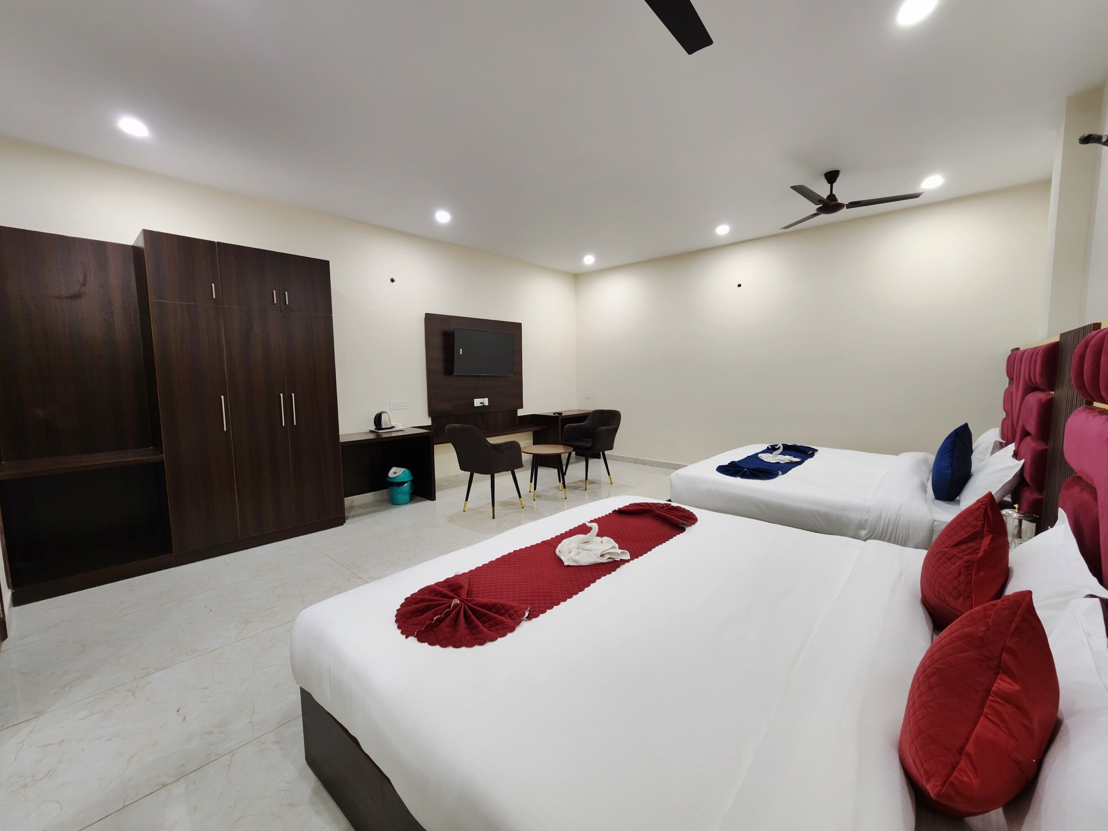 A hotel room with two beds, a desk, a TV, and a wardrobe.