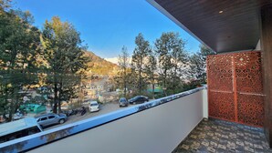 A balcony with a view of a street, trees, and buildings in the background. - Raina's BnB (Solan)