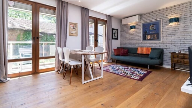 A modern living room with a dining table, chairs, a sofa, and a patterned rug. - Central 1-bedroom Apartment (Plovdiv)
