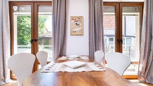 A dining area with a wooden table, white chairs, and a painting on the wall. - Central 1-bedroom Apartment (Plovdiv)