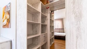 A walk-in closet with open shelving and a bed in the adjacent room. - Central 1-bedroom Apartment (Plovdiv)