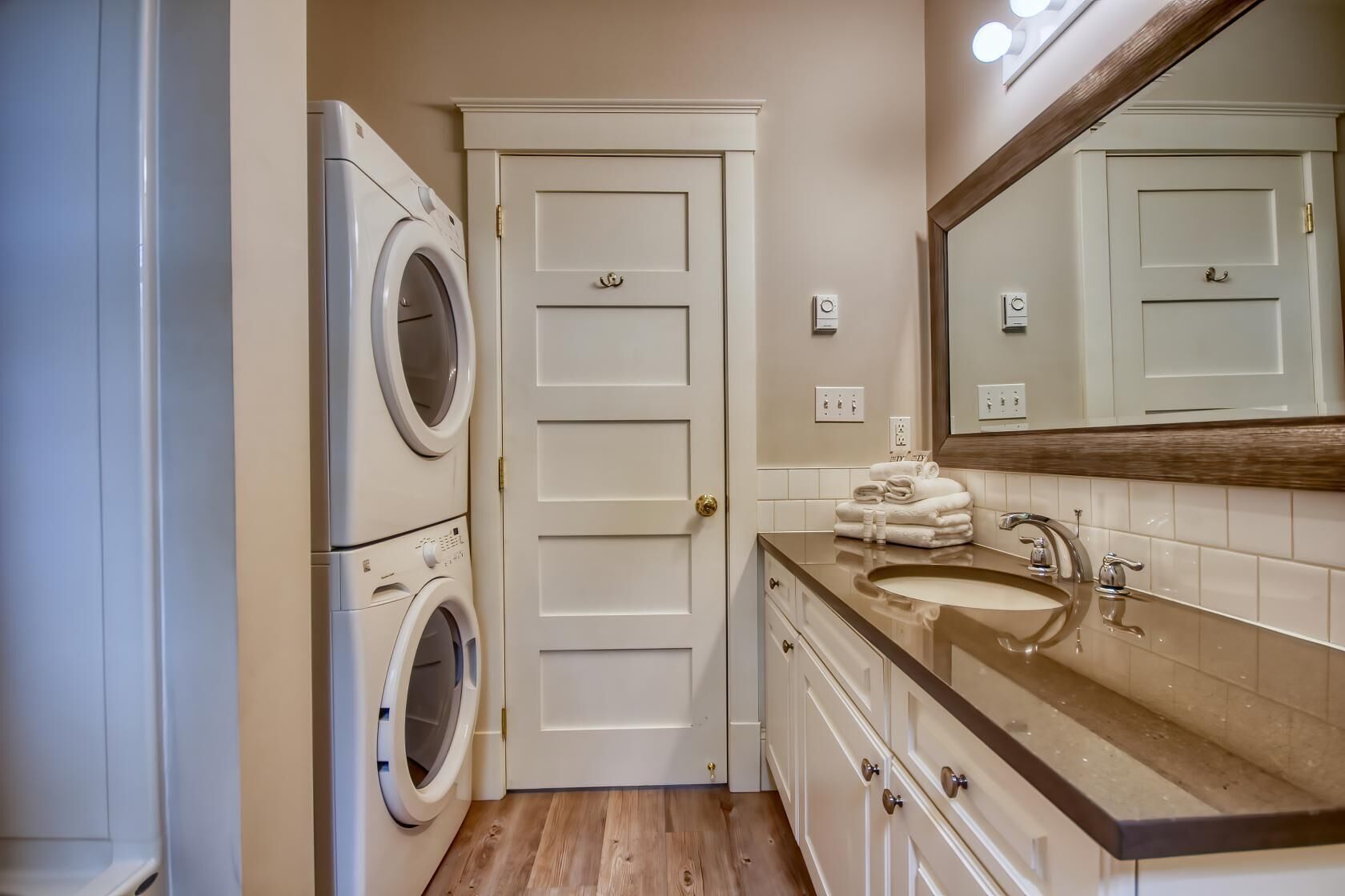 Une petite salle de bain équipée d’un lave-linge, d’un lavabo et d’un miroir.