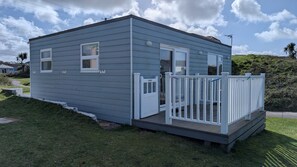 Une petite maison mobile d’un seul étage, dotée d’une véranda, d’une porte et d’une fenêtre.