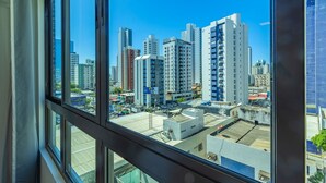 A view from a window overlooking a cityscape with high-rise buildings and a clear blue sky.
