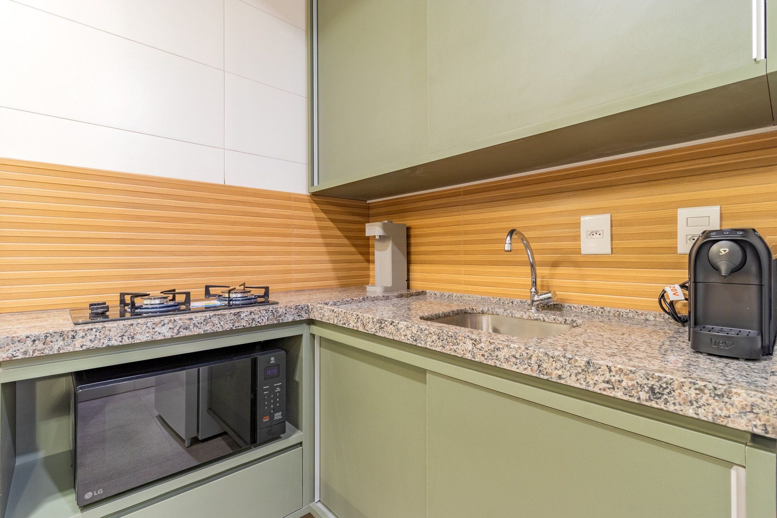 Una cocina equipada con microondas, cafetera y lavabo.