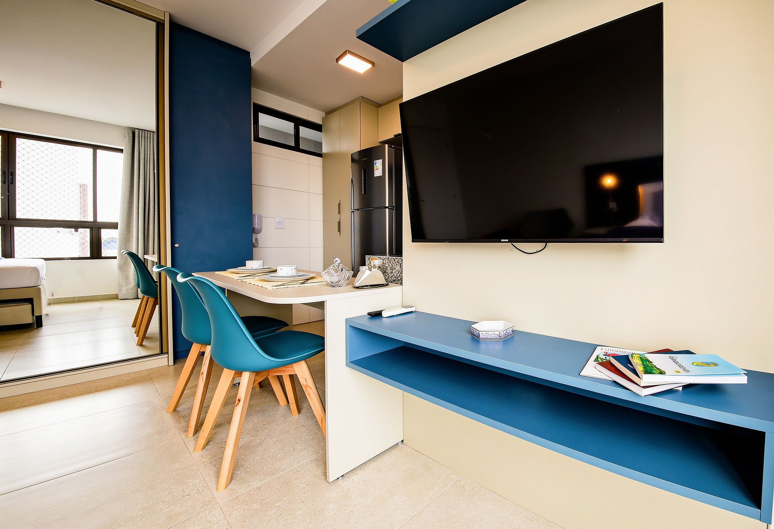 Una cocina moderna con comedor, refrigerador, televisor de pantalla plana y ventana con vista.
