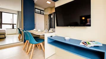 Una cocina moderna con comedor, refrigerador, televisor de pantalla plana y ventana con vista.