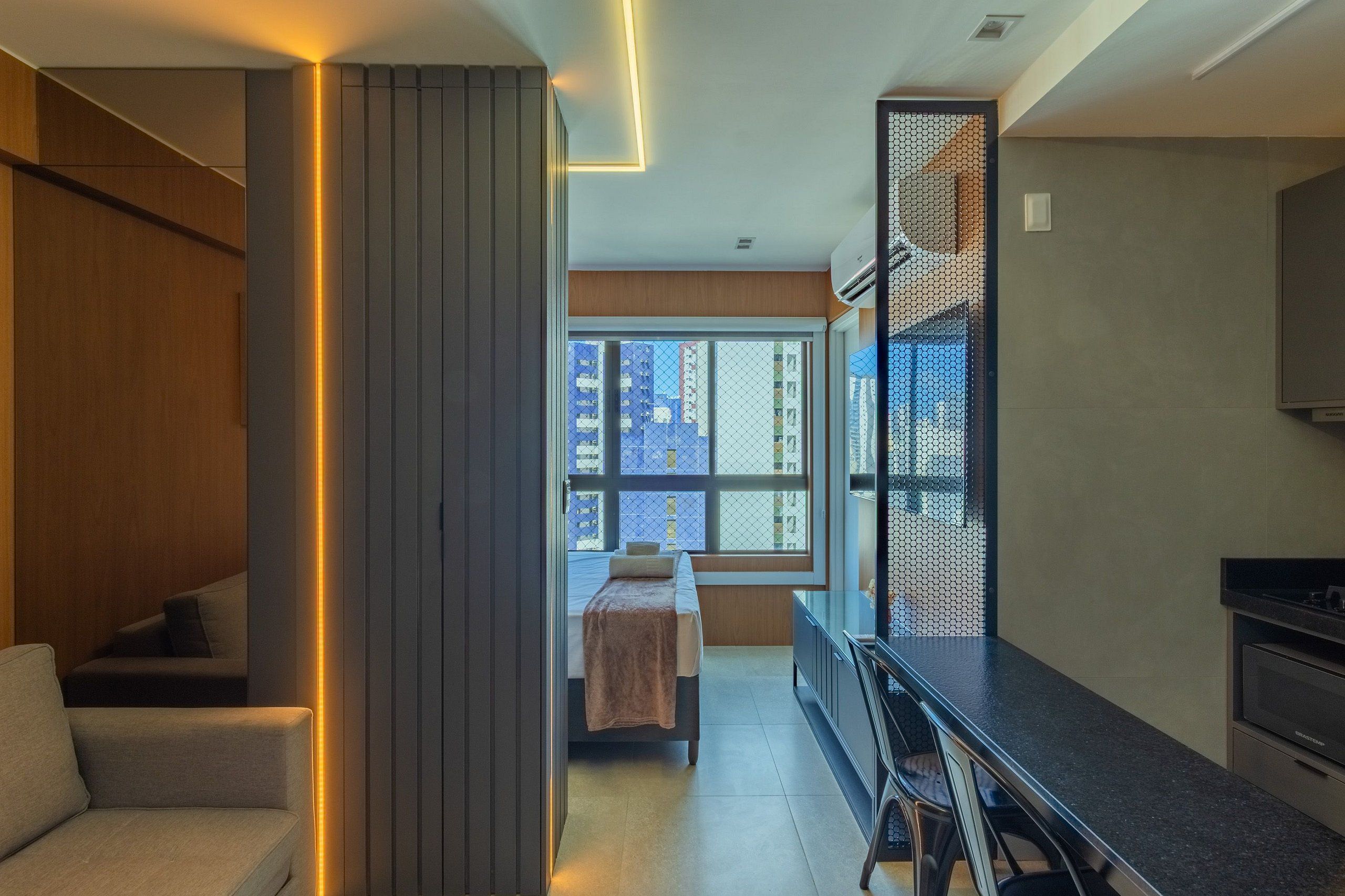 Quarto de hotel moderno com cama, um espaço para refeições e uma cozinha.