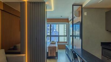 Quarto de hotel moderno com cama, um espaço para refeições e uma cozinha.