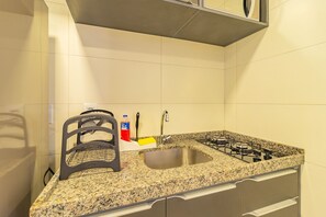 Una cocina con encimera de granito, pileta de acero inoxidable y estufa a gas.