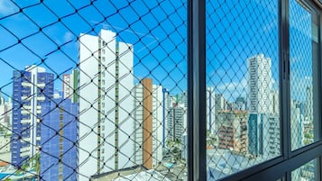 Visão da cidade através de uma cerca de arame, com edifícios altos ao fundo.