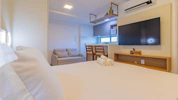 Una habitación de hotel con cama, televisor, escritorio y kitchenette.