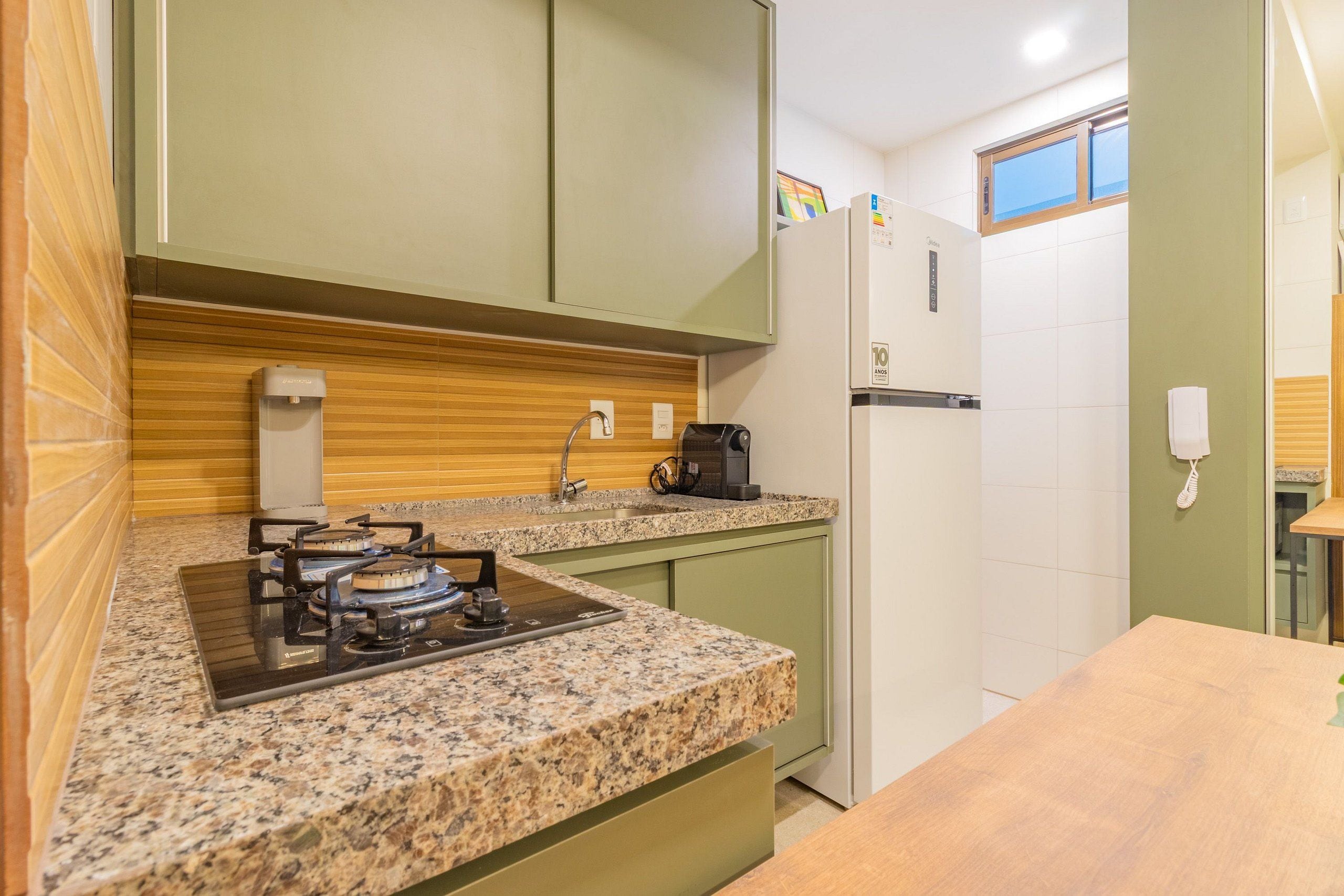 Uma cozinha compacta com fogão a gás, pia e geladeira.