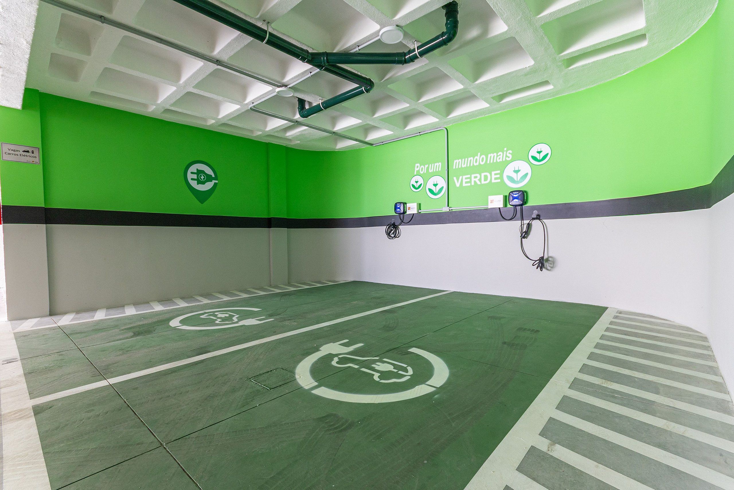 Interior verde y blanco con estaciones de carga para vehículos eléctricos y un letrero que indica un espacio verde.