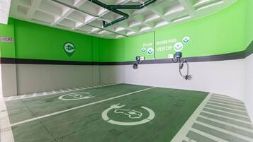 Interior verde y blanco con estaciones de carga para vehículos eléctricos y un letrero que indica un espacio verde.
