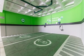Ein helles Interieur in Grün und Weiß mit Ladestationen für Elektrofahrzeuge und einem Schild, das einen Grünbereich kennzeichnet.