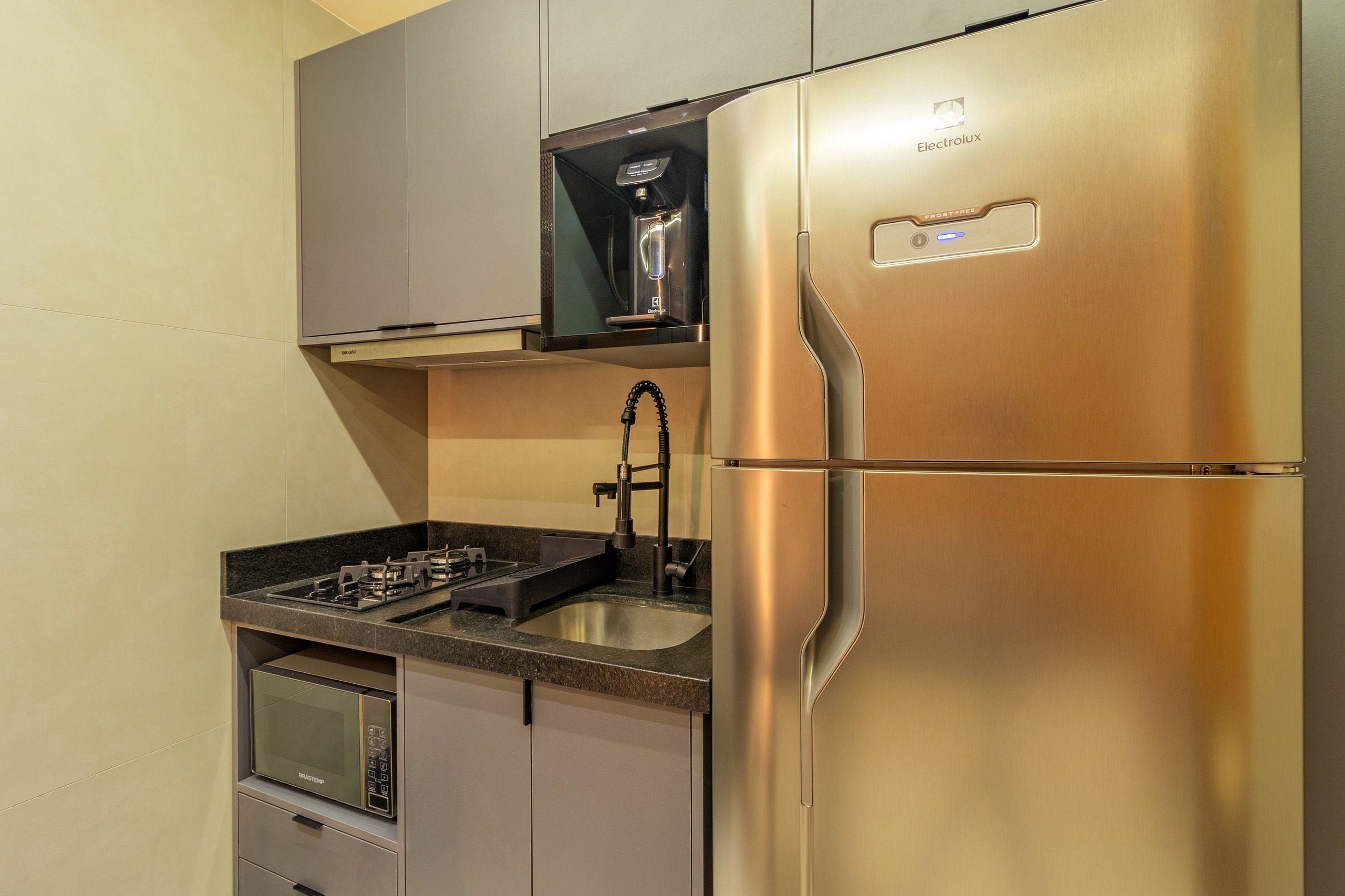 A modern kitchen with a stainless steel refrigerator, a built-in microwave, and a coffee machine.