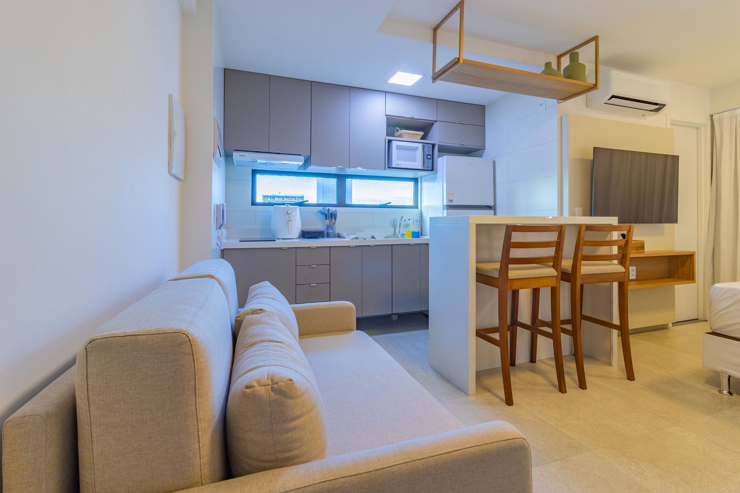 Una cocina moderna con microondas integrado, una zona de comedor con sillas de madera y un sofá en la sala de estar.