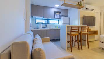 Una cocina moderna con microondas integrado, una zona de comedor con sillas de madera y un sofá en la sala de estar.