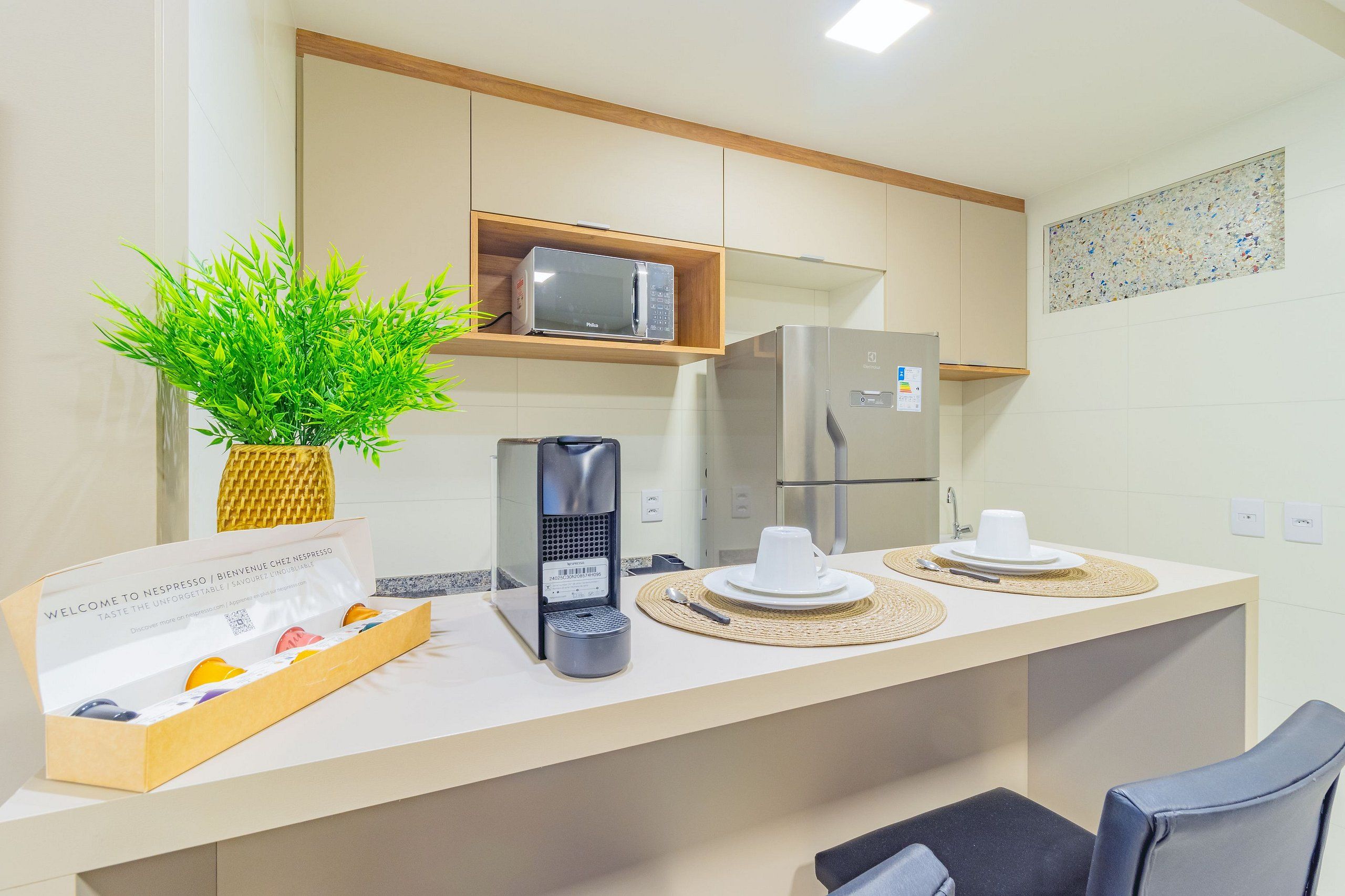 Una cocina moderna con cafetera, microondas y una cesta de bienvenida.