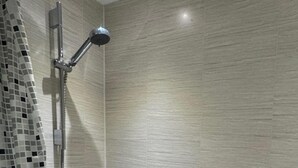 A bathroom with a shower, a bathtub, and a tiled wall.