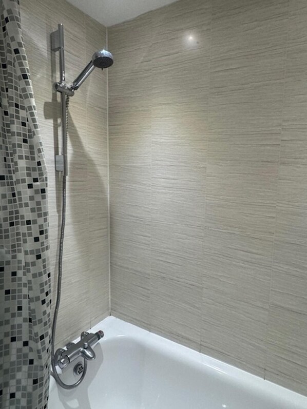 A bathroom with a shower, a bathtub, and a tiled wall. - Lewisham - Apartment - Sleeps 5 - Central Location (London)