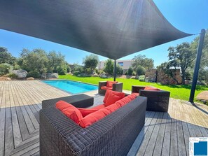A wooden deck with a pool, outdoor furniture, and a large umbrella.