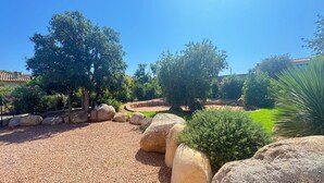 A landscaped garden with large rocks, trees, and a clear blue sky.