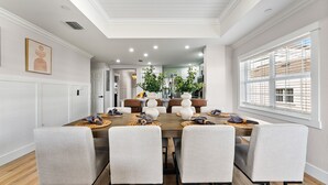 A dining area with a long table, six chairs, and a modern kitchen in the background. - Beautiful Condo with Golf Course Views, Kids Bedroom and Near Attractions (Kissimmee)