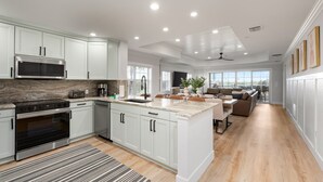 A modern kitchen with white cabinetry, a stainless steel microwave, and a built-in oven. - Beautiful Condo with Golf Course Views, Kids Bedroom and Near Attractions (Kissimmee)