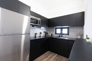 Een koelkast, kookgerei, borden en bestek, een eettafel