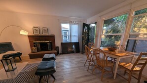 Una sala moderna con chimenea, un comedor con sillas de madera y un amplio ventanal con cortinas.