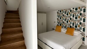 A bedroom with a white bed, wooden staircase, and a geometric-patterned wall. - Chez Elena with shared terrace overlooking the sea Ravello (Ravello)