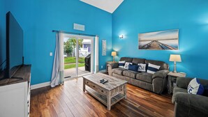 Ein Wohnzimmer mit blauer Wand, einem Holztisch, einer Couch und einem Gemälde.