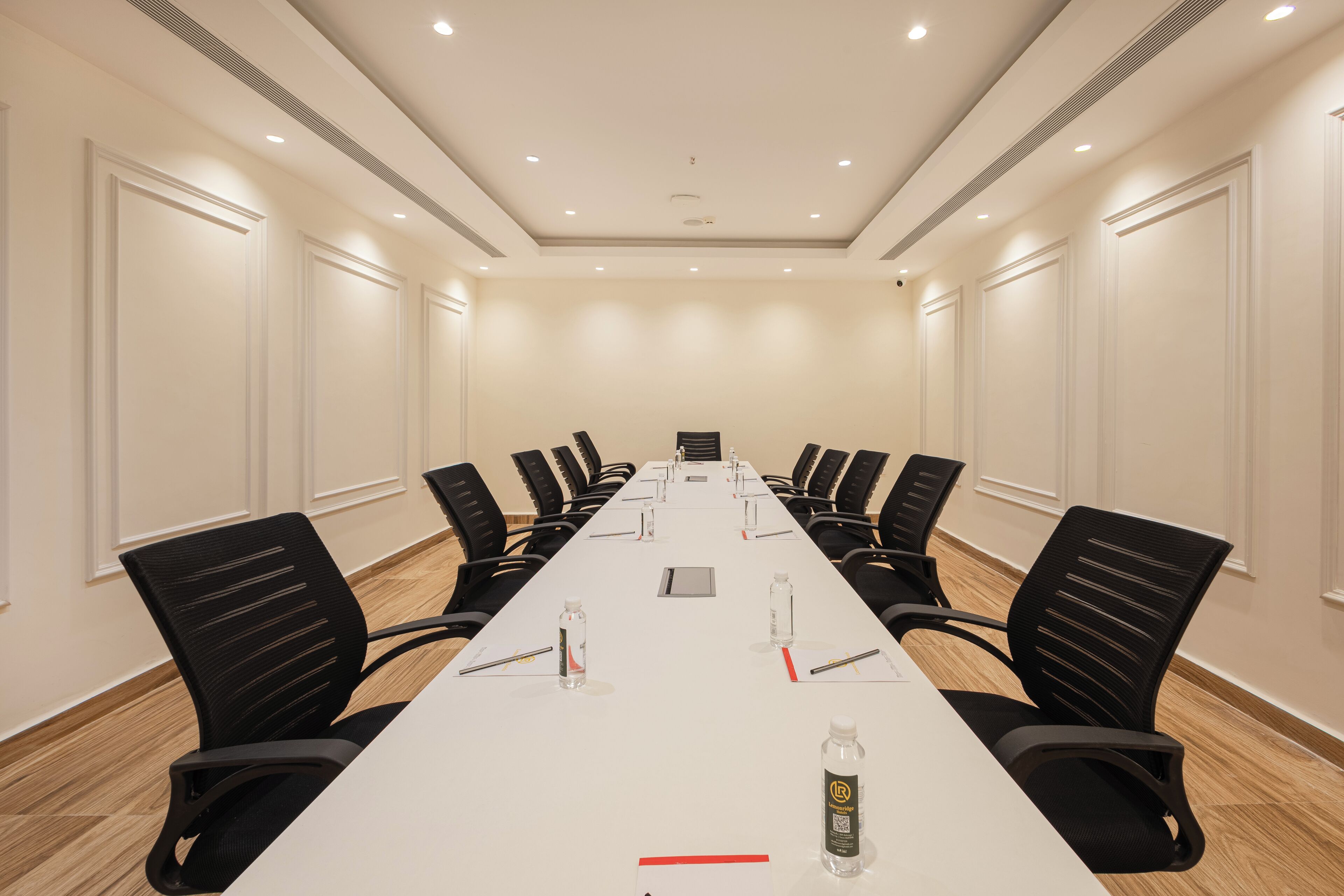 A conference room with a long table, black chairs, and a whiteboard.
