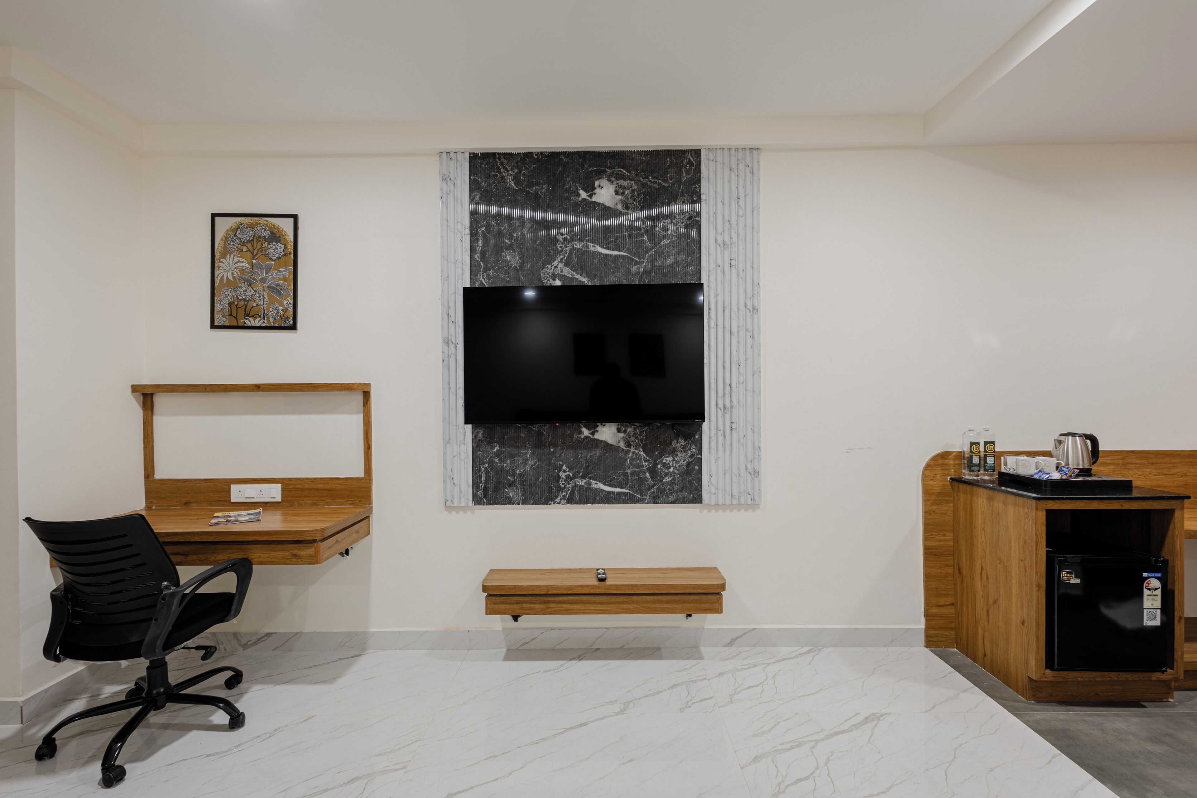 Un espace de bureau moderne avec un bureau en bois, un fauteuil de bureau noir et un téléviseur à écran plat fixé au mur.