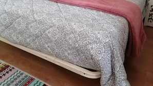 A bedroom with a patterned bedspread, a pink blanket, and decorative pillows.