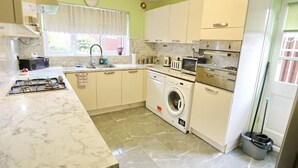A kitchen with a gas stove, microwave, oven, and washing machine.