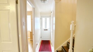 A hallway with a red carpet leading to a white door at the end.