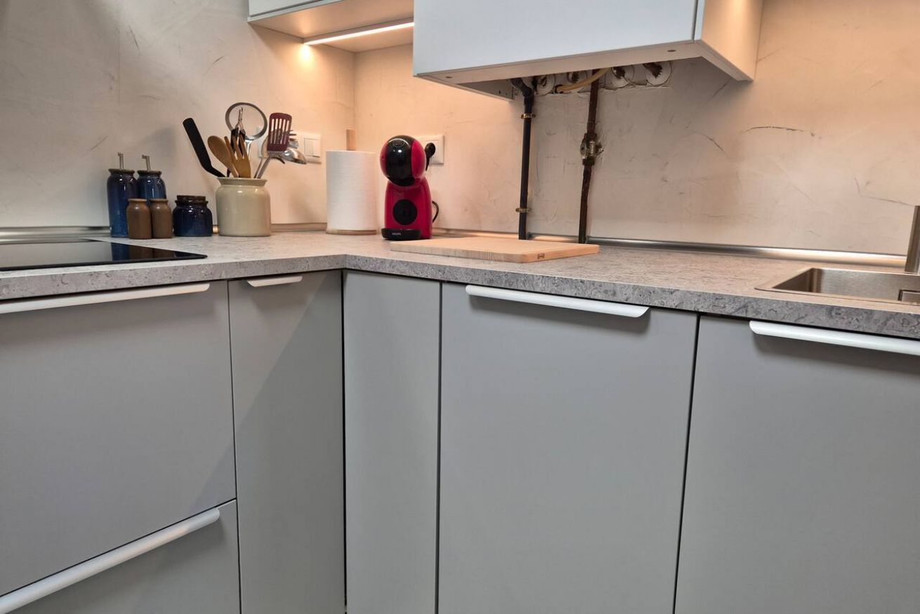A kitchen with white cabinets, a countertop, and a red appliance.