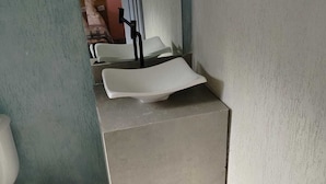 Une petite salle de bain avec un lavabo blanc, des toilettes et une poubelle.